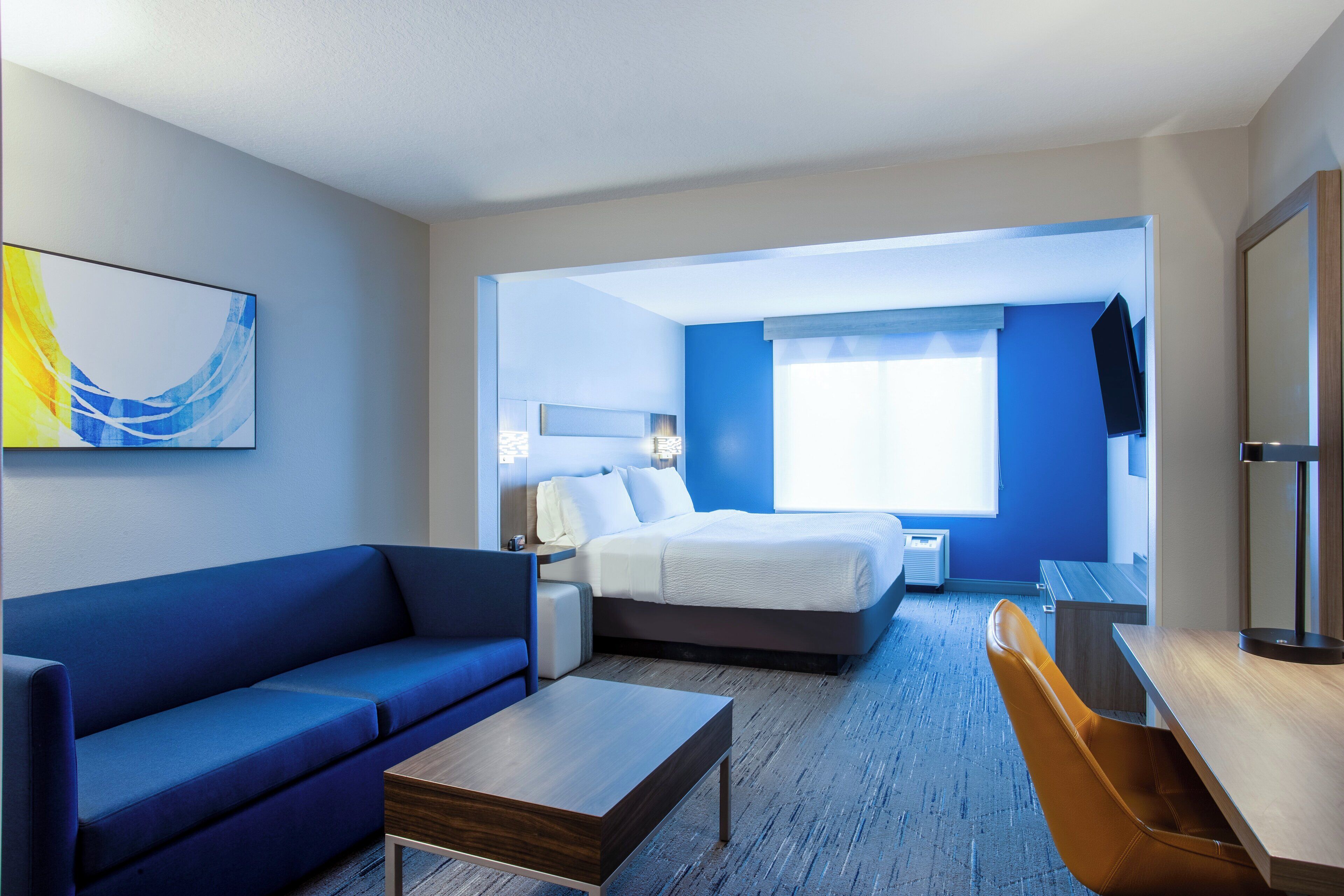 A hotel room with a bed, a sofa, a desk, and a chair.