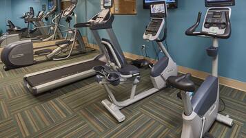 Un gimnasio con cintas de correr, elípticas y una bicicleta estática, equipado con pantallas digitales y monitores de frecuencia cardíaca.