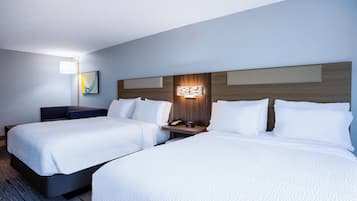 Habitación de hotel con dos camas, una mesita de noche con teléfono, una lámpara y un aplique de pared.