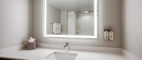 Un baño moderno con un espejo grande, un lavamanos y un dispensador de toallas.