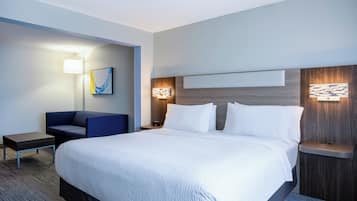 Habitación de hotel con una cama grande, un escritorio, una silla y dos lámparas de pared.