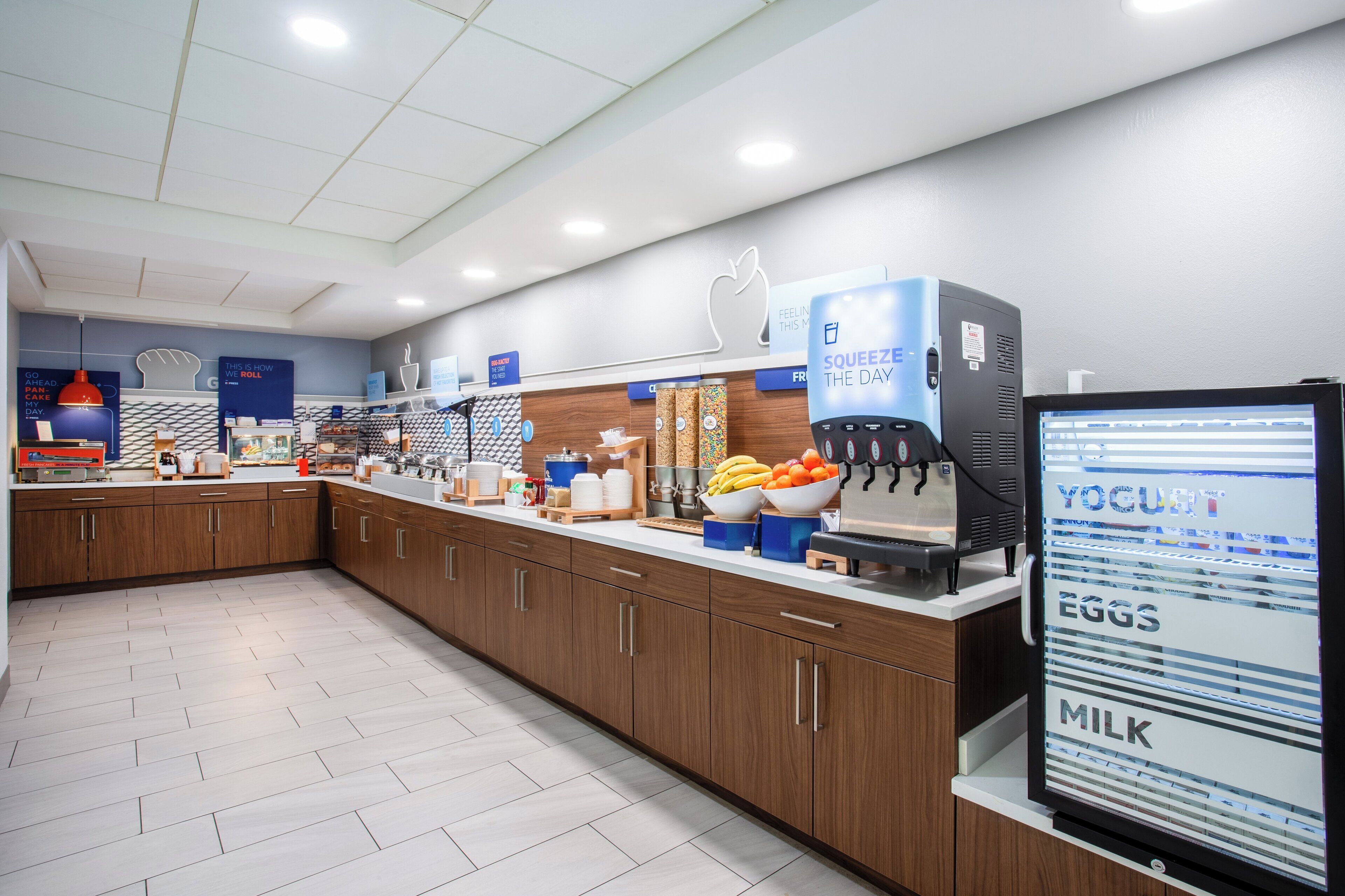 A modern kitchen area with a coffee machine, a yogurt dispenser, and various food items on the counter.