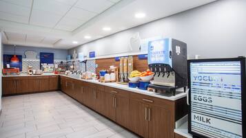 A modern kitchen area with a coffee machine, a yogurt dispenser, and various food items on the counter.
