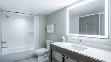 A modern bathroom with a bathtub, toilet, and vanity.