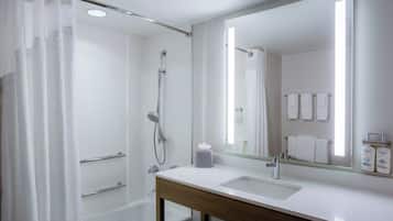 Un baño moderno con ducha, lavamanos y espejo.