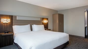 Una habitación de hotel moderna con una cama grande, cabecero de madera y apliques empotrados en la pared.