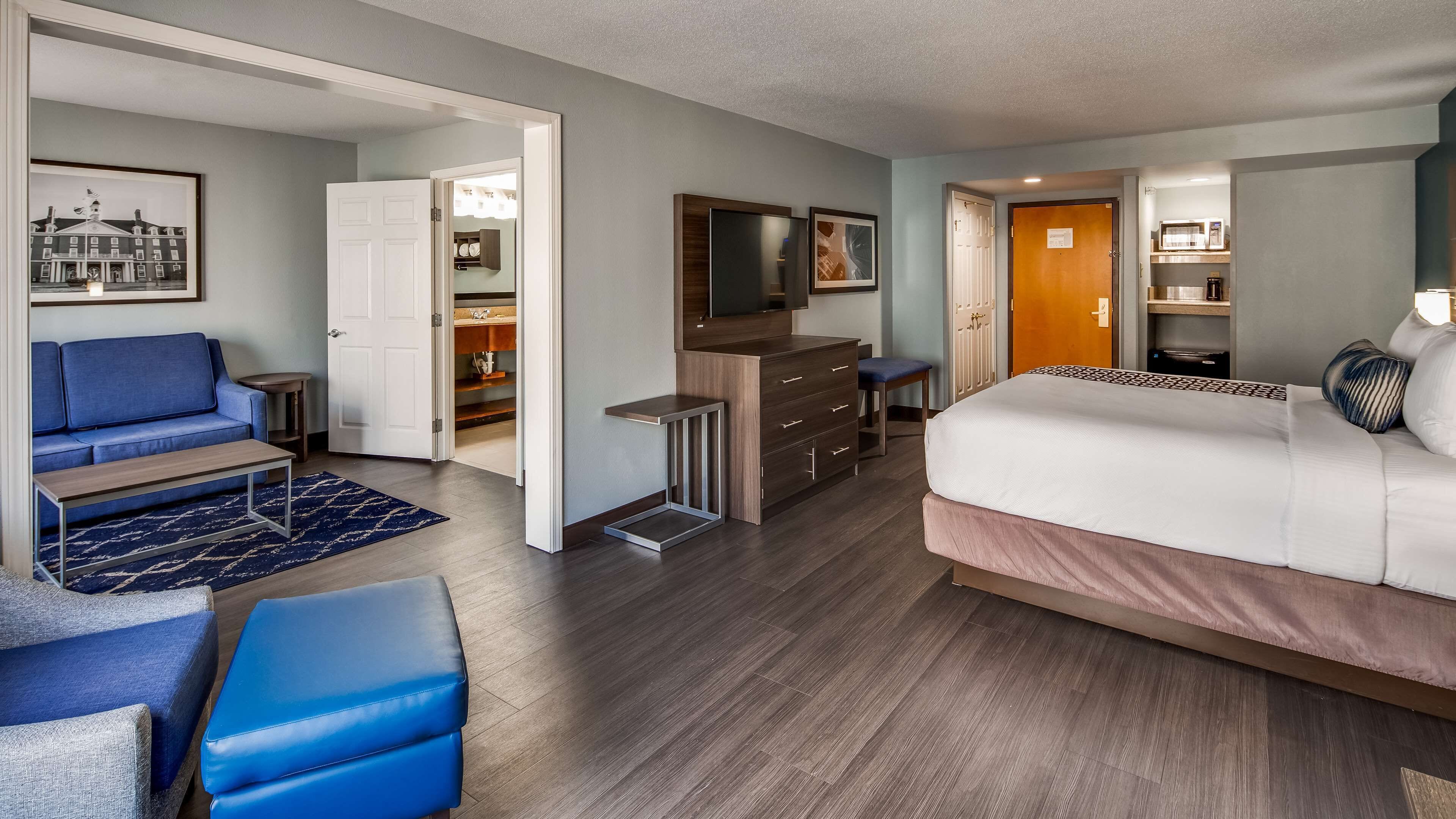 A hotel room with a bed, a sofa, a TV, a desk, and a closet.
