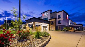 A Best Western Plus hotel with a modern design, featuring a stone facade, large windows, and a well-maintained garden with red flowers. - Best Western Plus Champaign/Urbana Inn (Champaign)