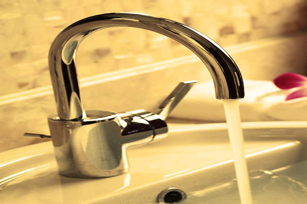 Un lavabo de salle de bain avec un robinet chromé et de l’eau qui coule.