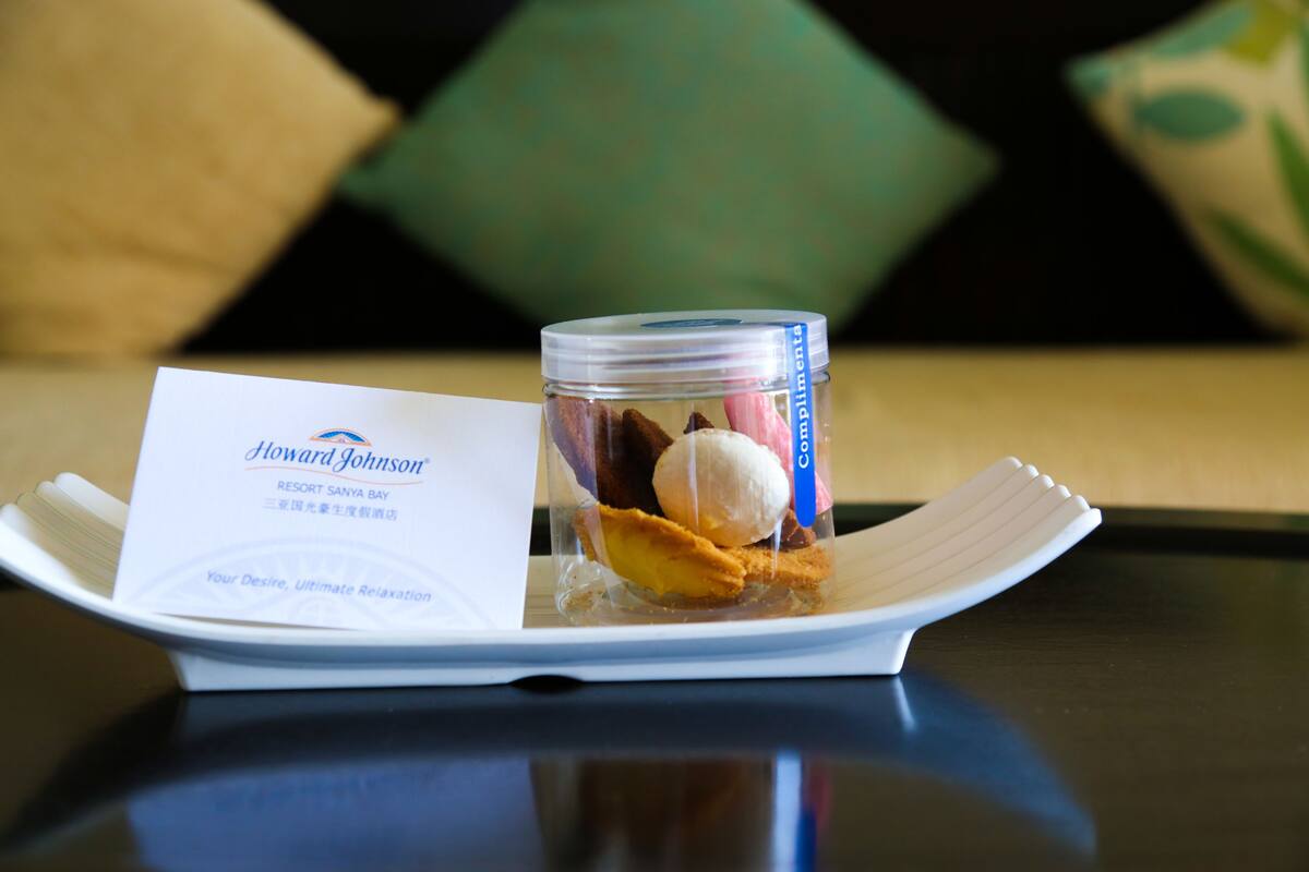 Un dessert composé d’un pot de crème glacée et de biscuits, le tout présenté sur une assiette blanche, accompagné d’une carte de visite.