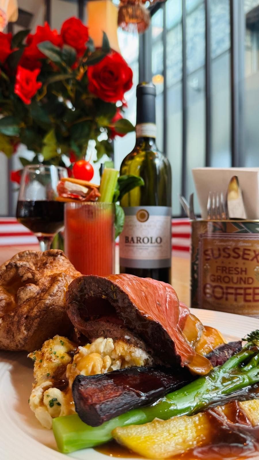 Une assiette de nourriture, une bouteille de vin Barolo, un verre de vin rouge et un récipient de café fraîchement moulu de Sussex.