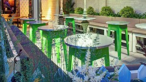 An outdoor patio area with round tables and chairs, a brick building in the background, and a covered seating area with hanging lamps. - Oddfellows Chester Hotel and Apartments (Chester)