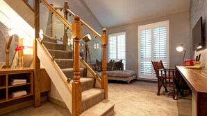 A cozy living room with a wooden staircase, a comfortable sofa, a dining area, and a large window with blinds. - Oddfellows Chester Hotel and Apartments (Chester)