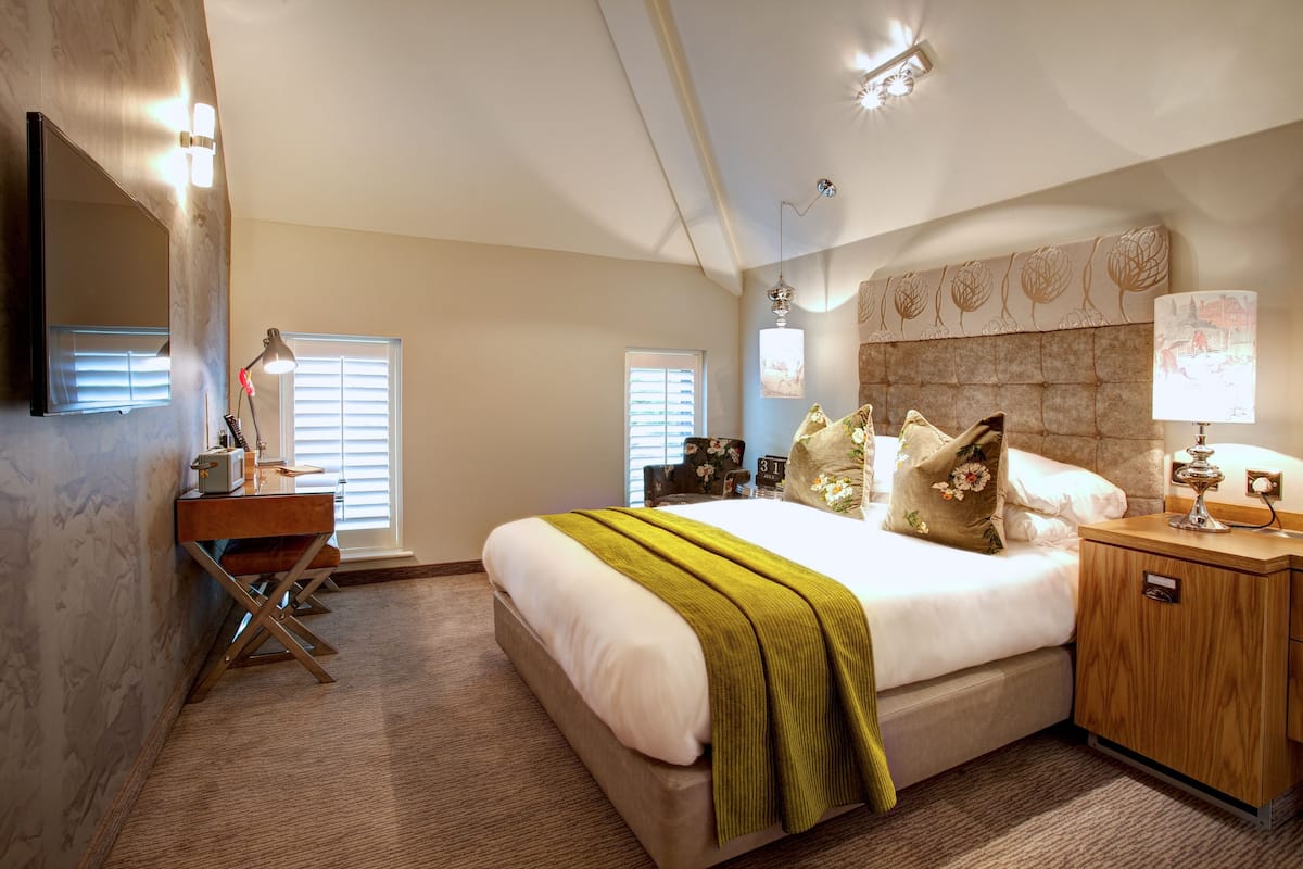 A hotel room with a large bed, bedside tables, a desk, and a mirror.