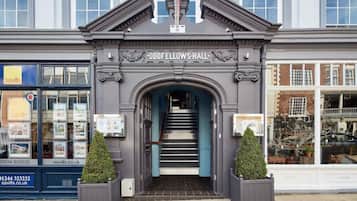 The entrance to Oddfellows Hall with a staircase leading up to the entrance, flanked by two potted plants.