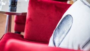 A dining area with red upholstered chairs, a table with wine glasses and a bottle, and a wall with fish illustrations.