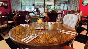 A round wooden table with a white rose, a candle, and a glass of orange juice. - Oddfellows Chester Hotel and Apartments (Chester)
