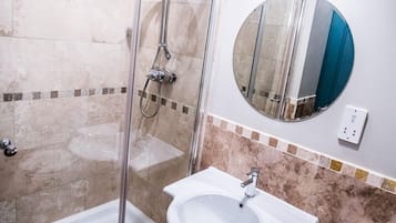 A bathroom with a glass-enclosed shower, a white sink, and a toilet.