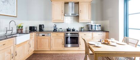 Eine moderne Küche mit Holzausstattung, Edelstahlgeräten und einem Essbereich mit Korbstühlen.