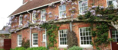 A traditional brick building with multiple windows and a garden in front.