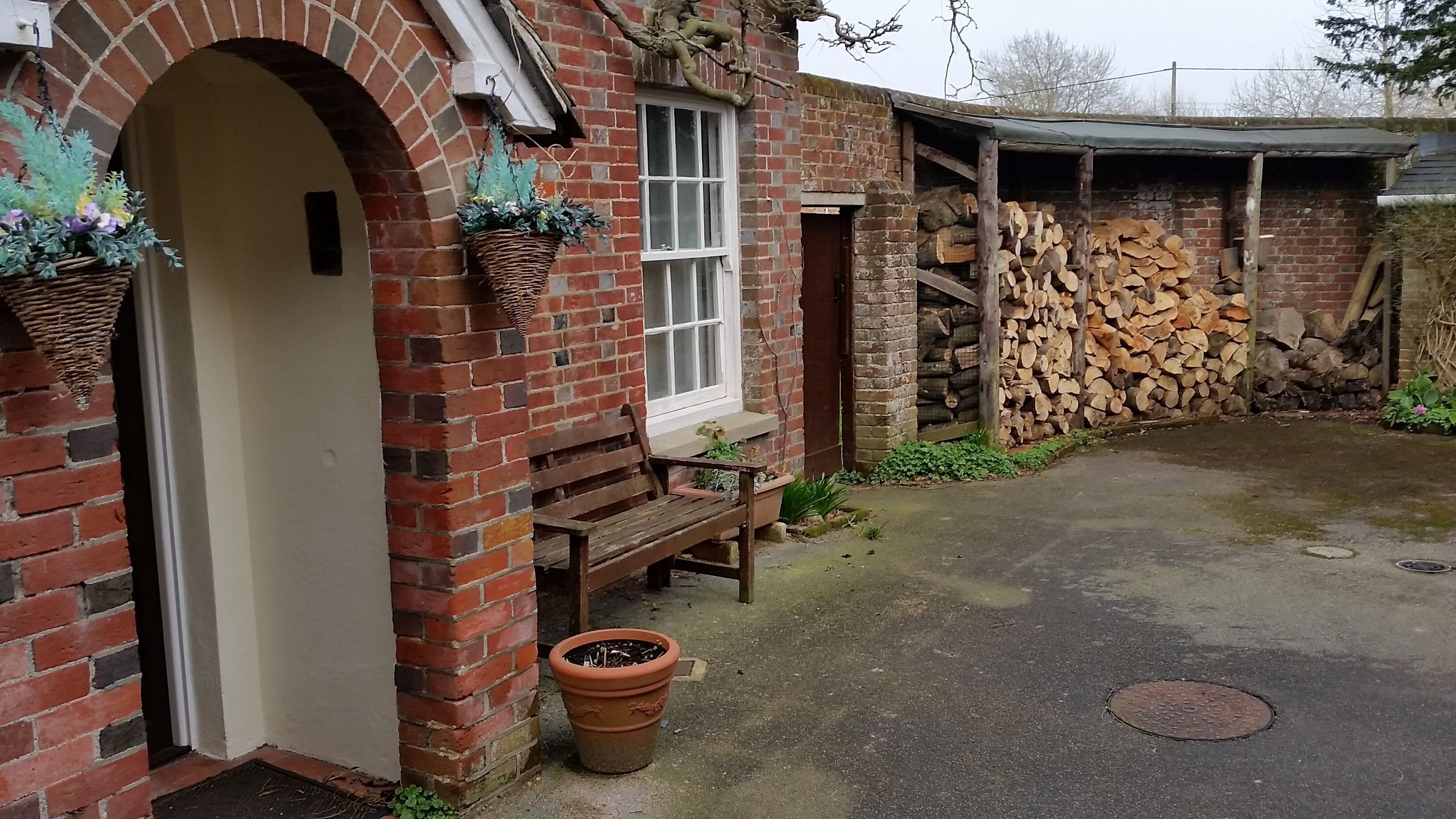 A brick building with a bench outside, a window, and a door.