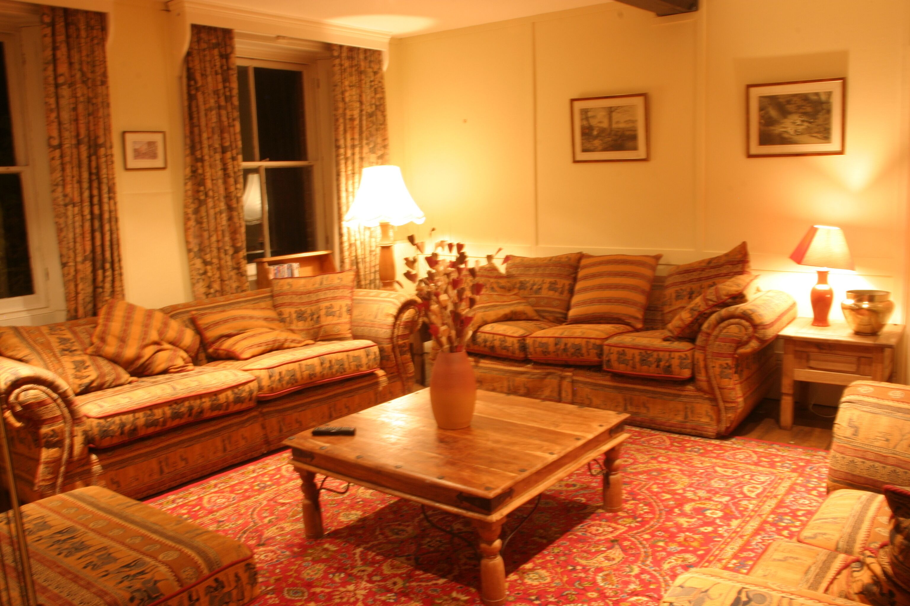 A cozy living room with patterned sofas, a wooden coffee table, and a vase with dried flowers.