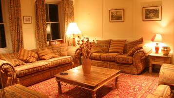 A cozy living room with patterned sofas, a wooden coffee table, and a vase with dried flowers.