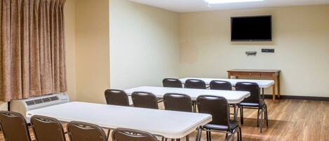 A conference room with a long table, chairs, a flat-screen TV, and a wooden floor.