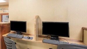 Un espacio de trabajo en un hotel con dos estaciones de computadora, cada una con teclado, ratón y monitor.