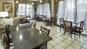 Un comedor con una mesa grande y sillas, un sofá y cortinas.