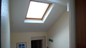 A skylight in a hallway with a fire exit sign and a framed picture on the wall. - The Chorlton (Blackpool)