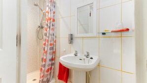 A bathroom with a shower, a sink, and a mirror. - The Chorlton (Blackpool)
