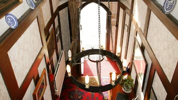 A narrow hallway with a red carpet, wooden paneling, and a hanging light fixture.
