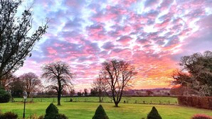 A rural landscape with a field, trees, and a sunset sky. - Collaven Manor Hotel (Okehampton)