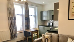 A compact living space with a kitchenette, a sofa, a dining table, and a chair. - Edgcumbe Guest House (Plymouth)