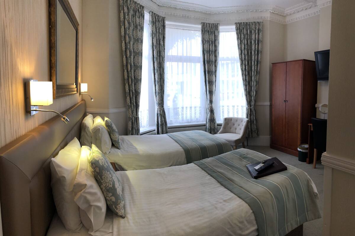 Ein Hotelzimmer mit zwei Betten, einem großen Spiegel, einem Fernseher und einem Kleiderschrank.