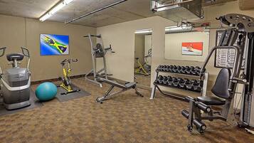 A gym with exercise equipment, a blue exercise ball, and dumbbells.
