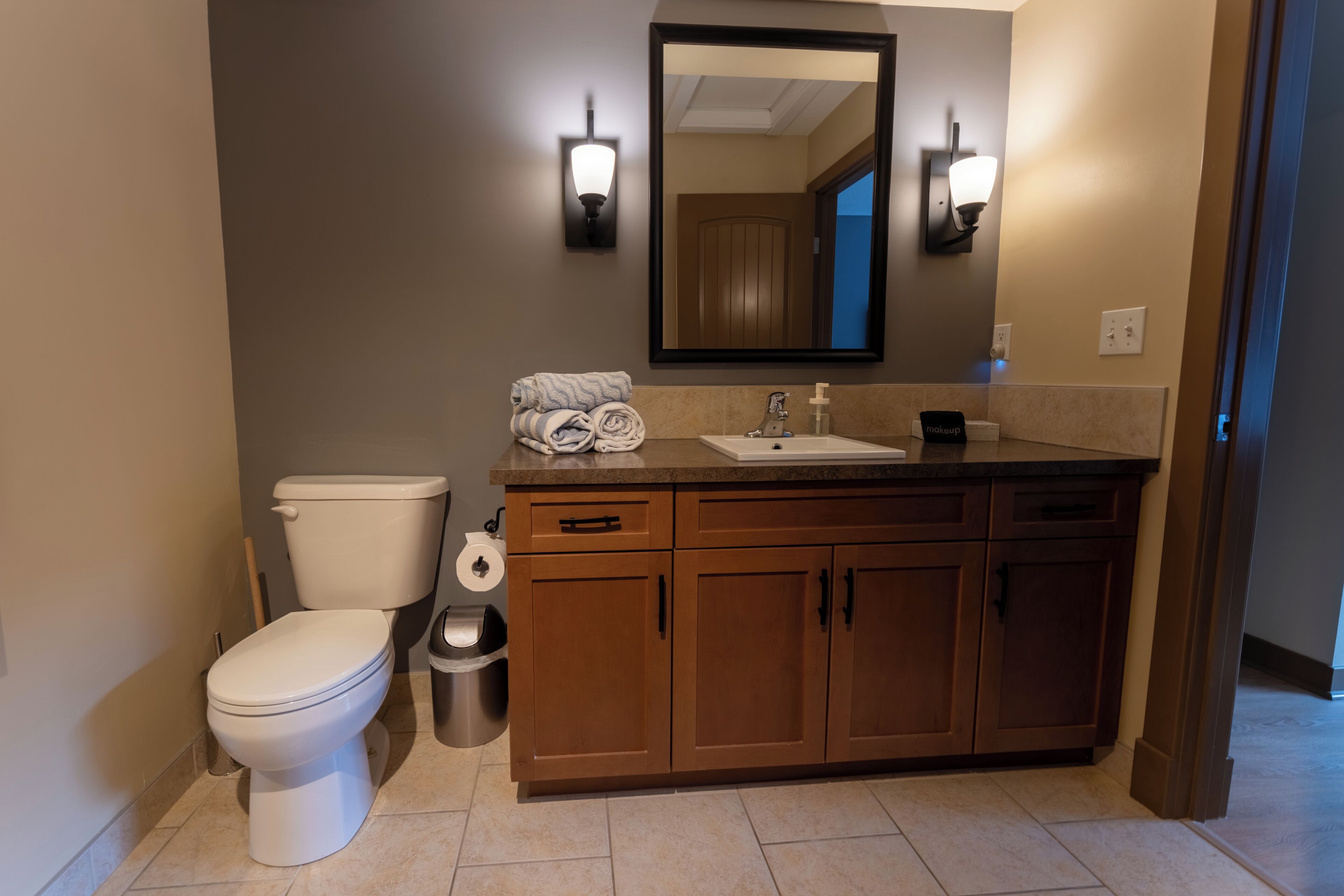 Un baño moderno con inodoro, lavamanos y armarios de madera.