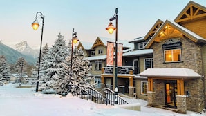 A hotel with a stone facade, wooden balconies, and a sign indicating it's open.
