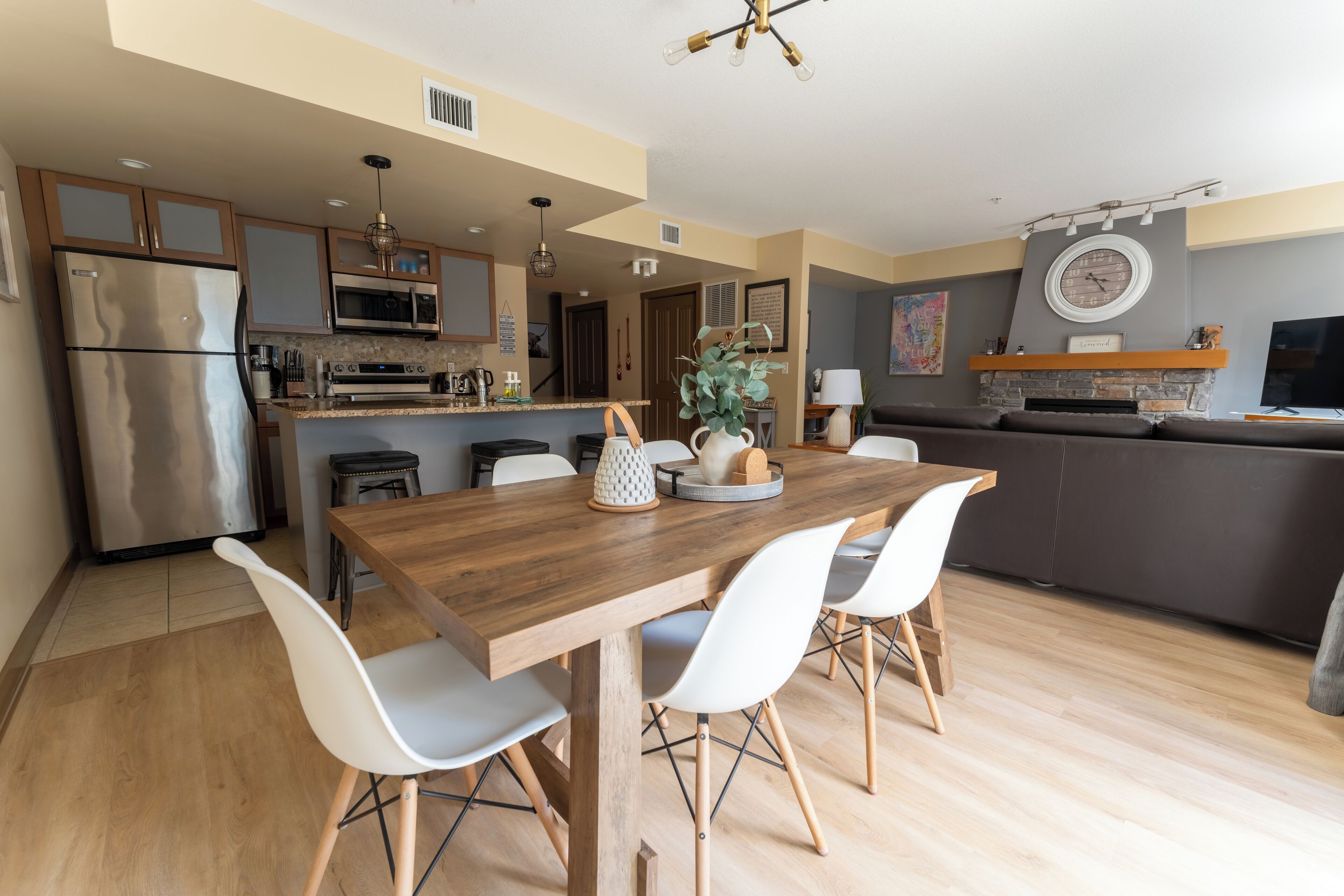Una cocina moderna con una mesa de comedor de madera, sillas blancas y un horno empotrado.