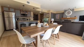 Una cocina moderna con una mesa de comedor de madera, sillas blancas y un horno empotrado.