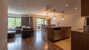 A modern kitchen with a central island, wooden flooring, and pendant lighting.