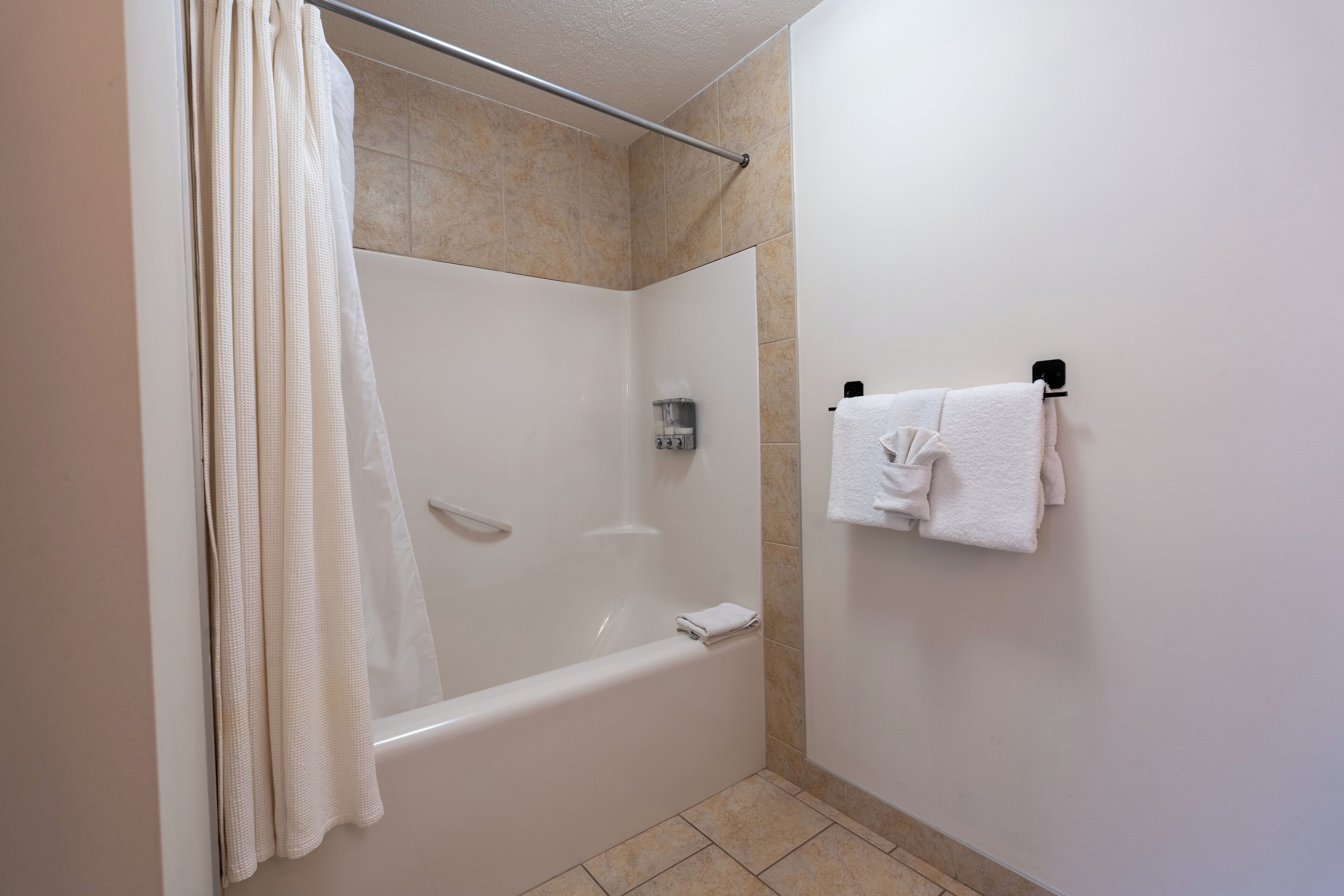 Une salle de bain avec une baignoire, un rideau de douche et un porte-serviettes avec des serviettes.