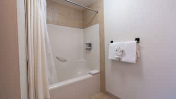 Une salle de bain avec une baignoire, un rideau de douche et un porte-serviettes avec des serviettes.