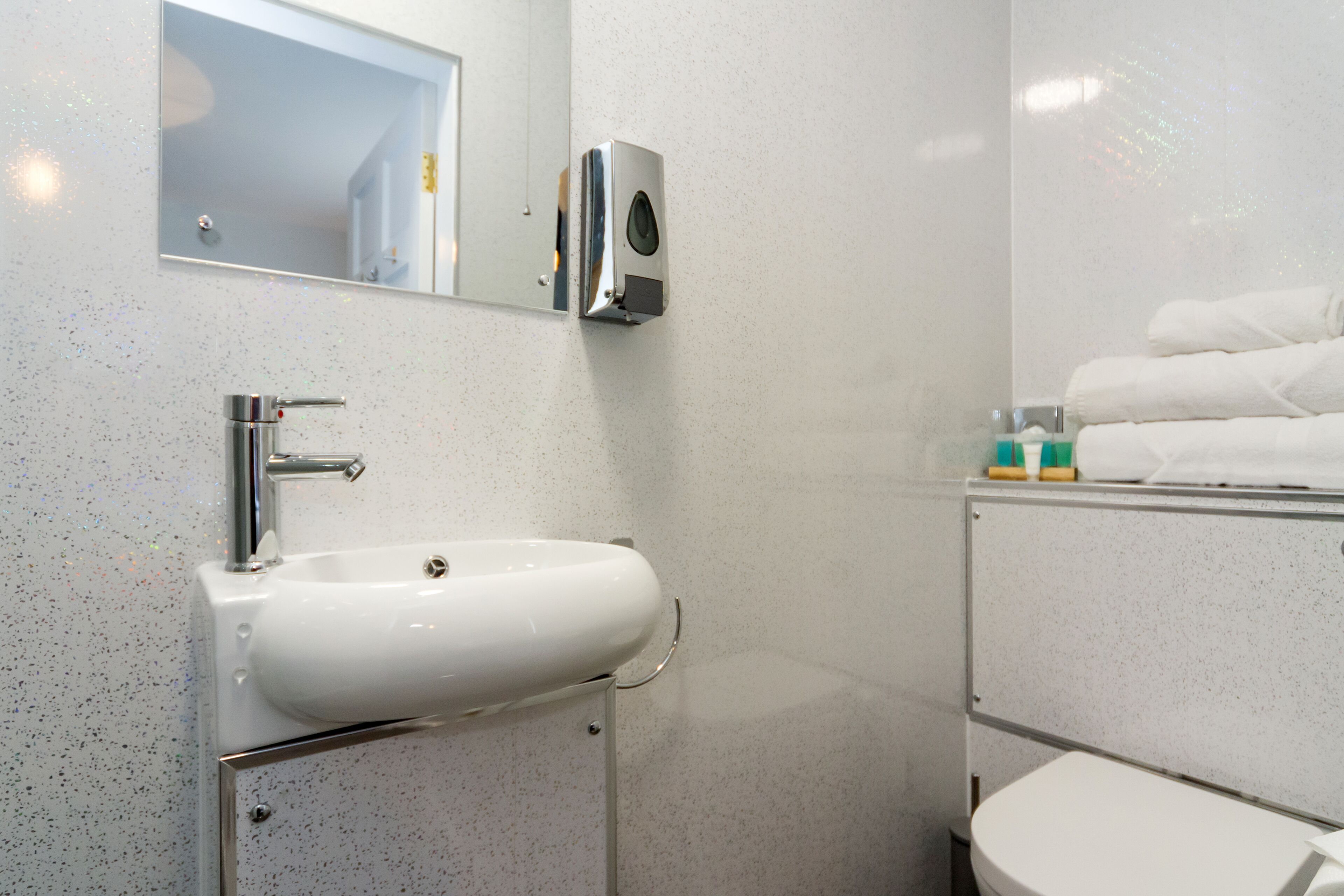 Une salle de bain avec un lavabo blanc, un miroir et des toilettes.
