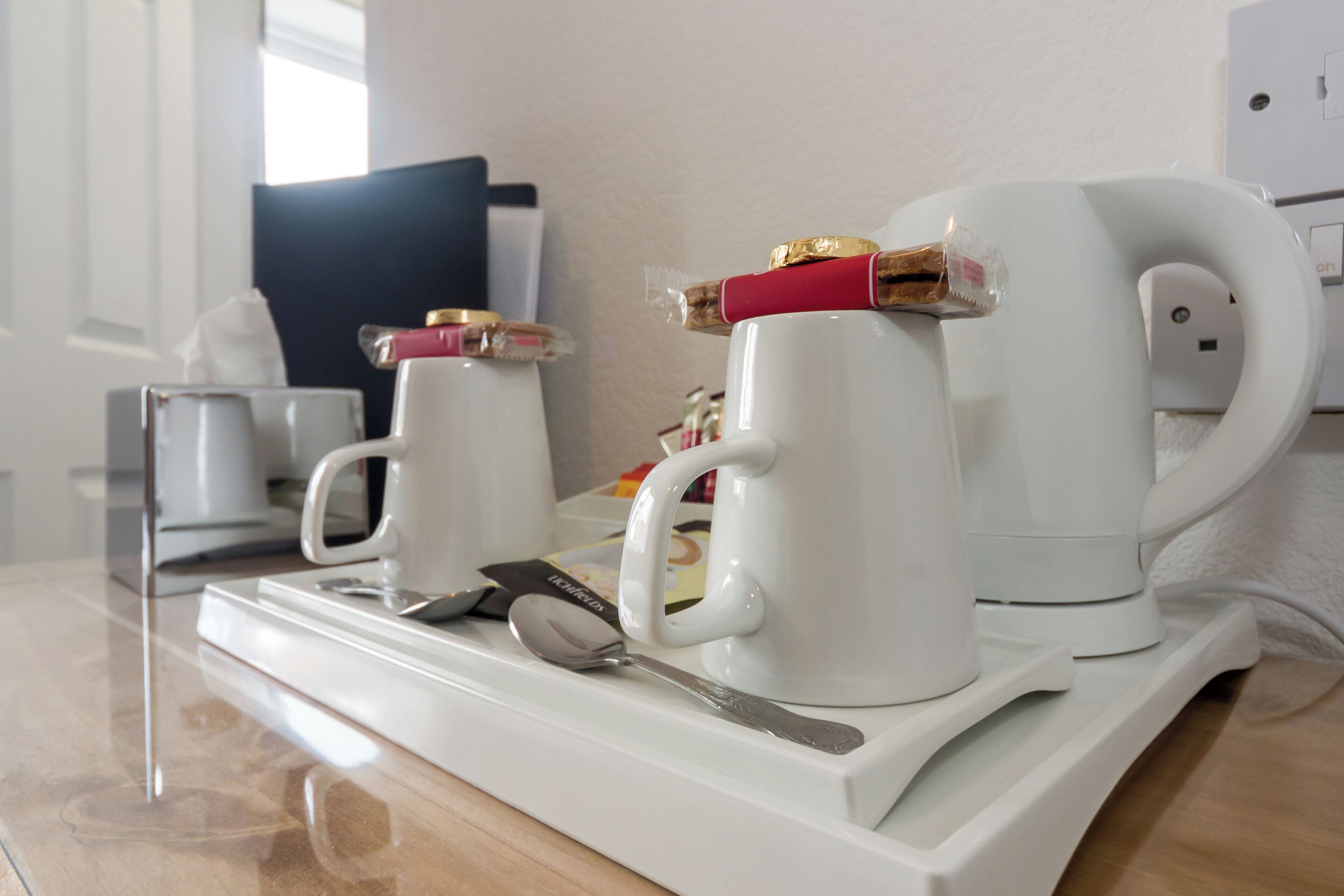 Un plateau de petit-déjeuner avec deux tasses blanches, une cuillère et un petit sachet de sucre.