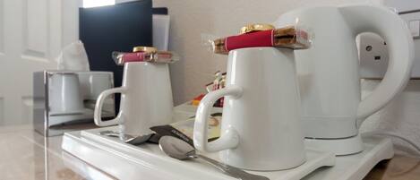 Un plateau de petit-déjeuner avec deux tasses blanches, une cuillère et un petit sachet de sucre.