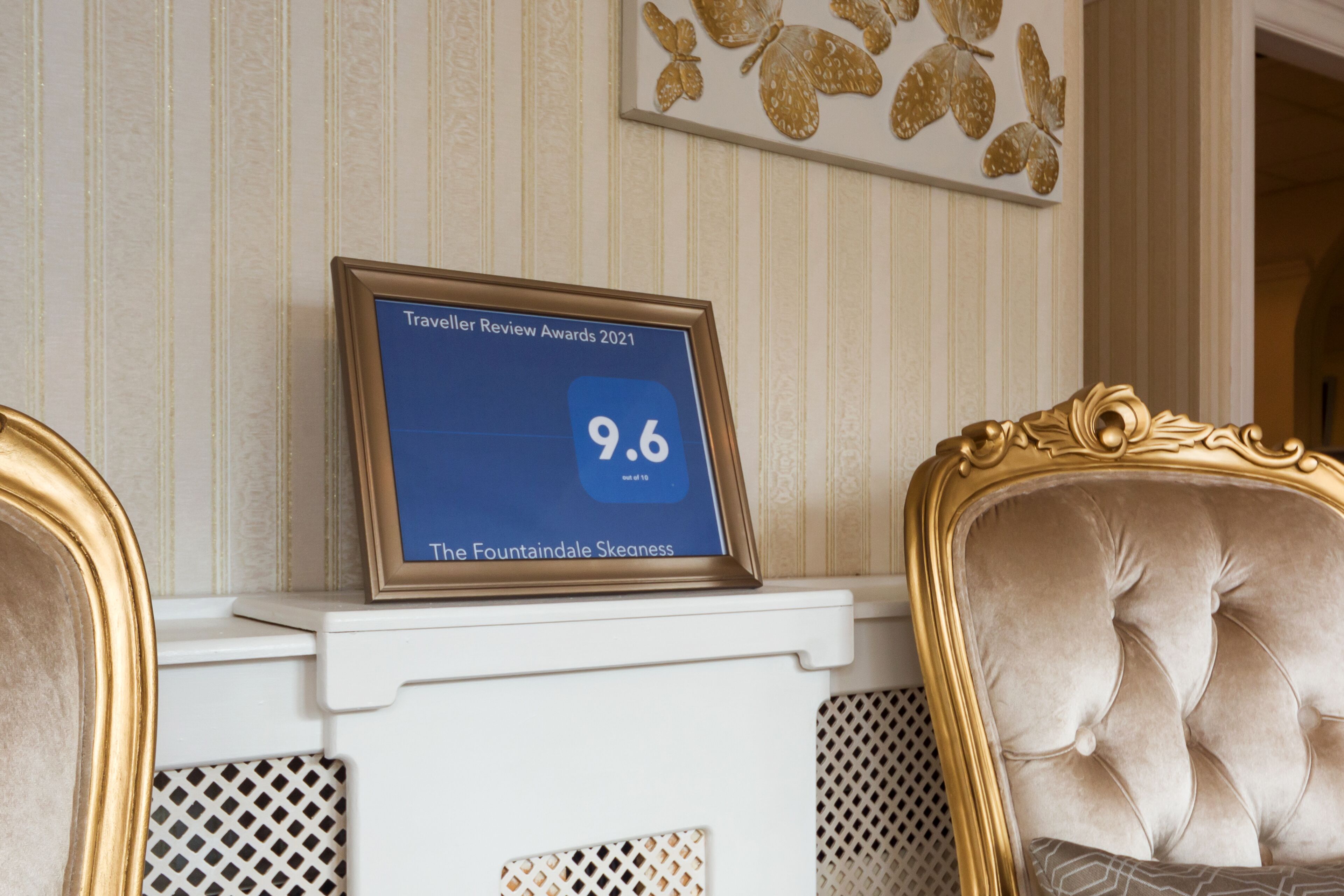 A framed award plaque on a white fireplace mantel with a 9.6 rating for The Fountainele Skeaness.