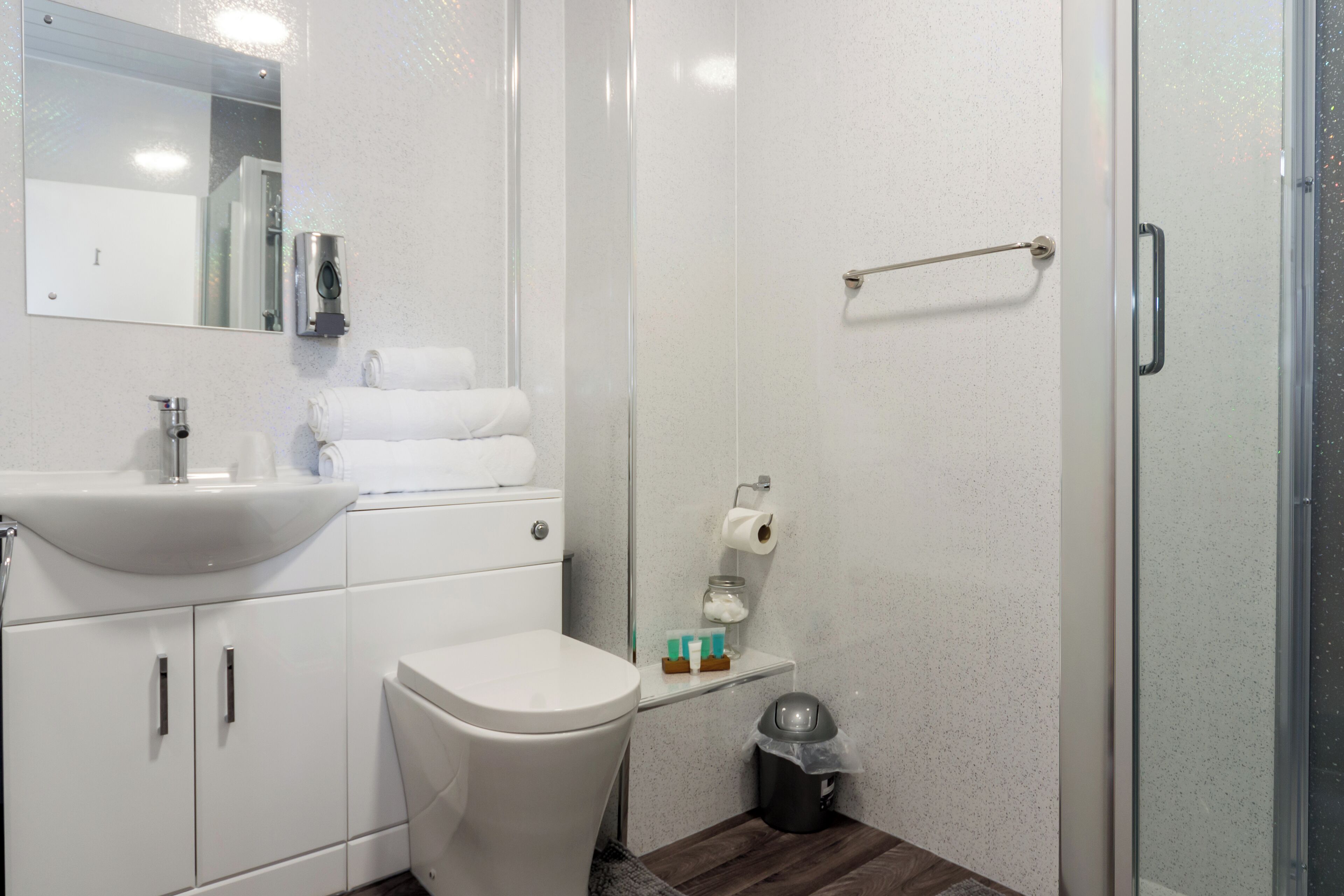 A modern bathroom with a white sink, toilet, and glass shower enclosure.