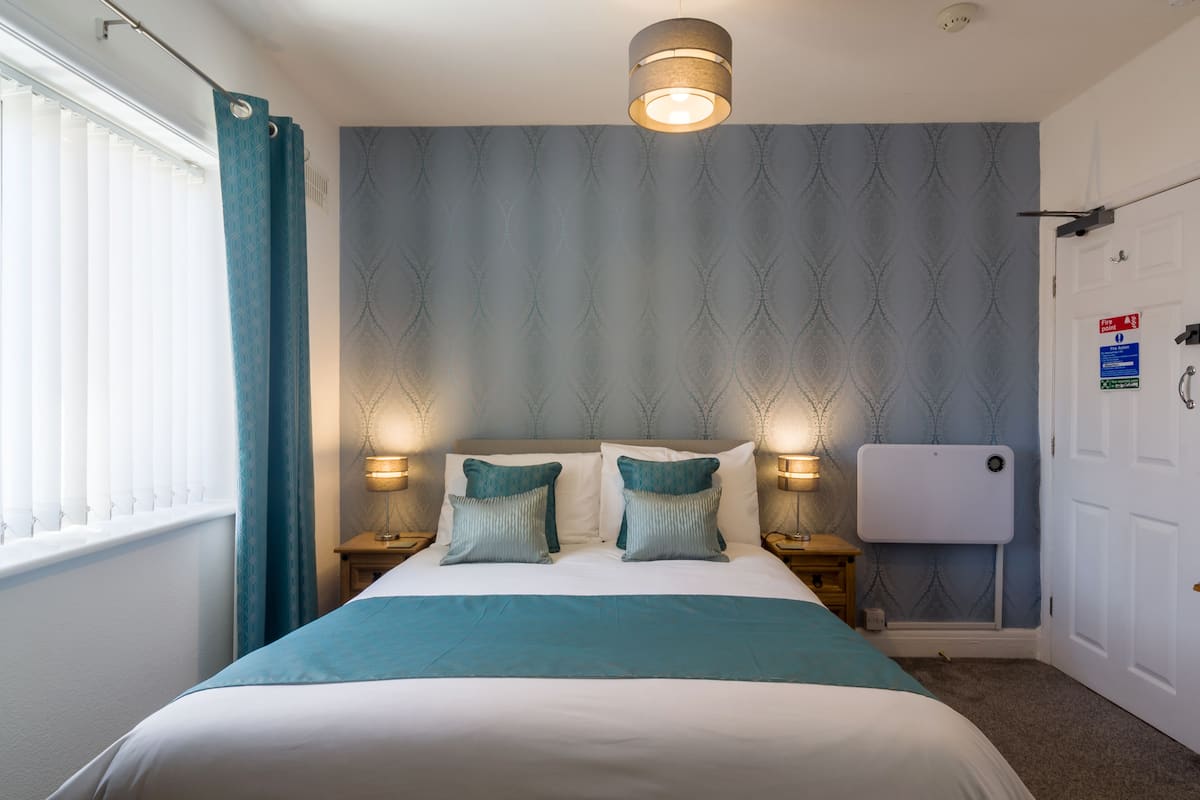 A neatly made bed with a blue and white bedspread, two matching pillows, and two bedside lamps.